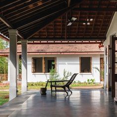 an empty porch with a table and chairs on it, in front of a house