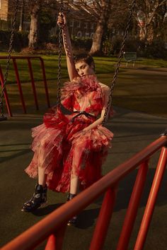 a woman in a red dress is sitting on a swing