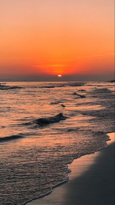 the sun is setting over the ocean with waves coming in and people walking on the beach