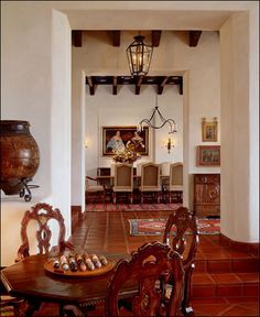 a dining room table and chairs with an ornate chandelier hanging from the ceiling