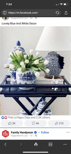 blue and white vases with flowers on a tray next to a lamp in a living room