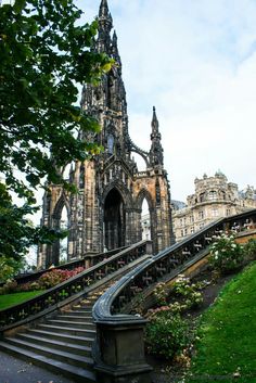 an old building with stairs leading up to it and flowers growing on the ground below