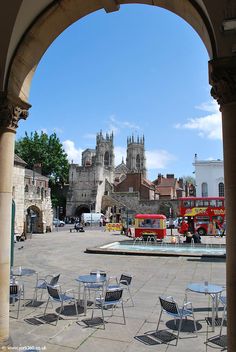 an archway leading to a courtyard with tables and chairs in front of a cathedral type building