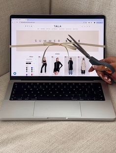 a person is holding scissors over a laptop