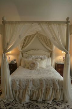 a white bed with curtains and pillows on it