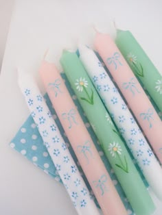 four candles are lined up on a table next to a plate with flowers and polka dot napkins