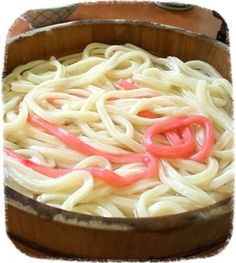 a wooden bowl filled with noodles and sauce