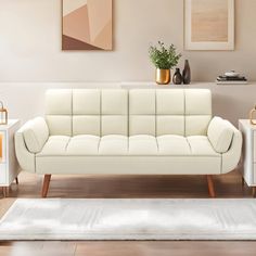 a white couch sitting on top of a hard wood floor next to two end tables