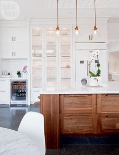 an instagramted photo of a kitchen with white cabinets and wood countertops