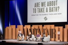 three people are sitting on chairs in front of a large screen that says, are we about to take a bath?