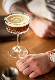 a man sitting at a table with a drink in front of him and his watch