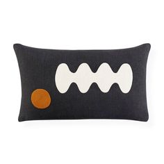 a black and white pillow with an orange circle on the front, and two wavy lines across the back