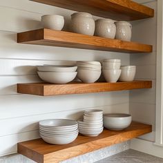 bowls and plates sit on wooden shelves in a white room with wood trimmings