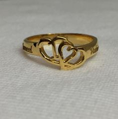 a gold ring with two hearts in the middle on a white cloth covered tablecloth