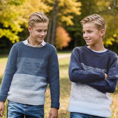 two young boys standing next to each other in front of some trees and grass with leaves on the ground