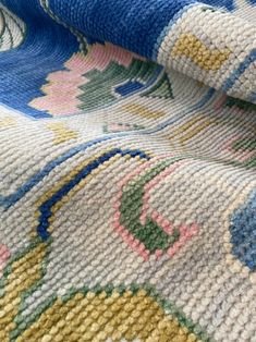 a multicolored rug is laying on top of a tablecloth that has been folded over