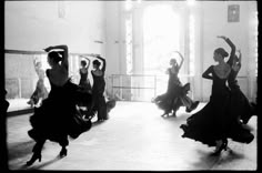 black and white photograph of women dancing in an old fashion dance hall with sun shining through the windows