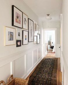 a long hallway with pictures on the wall and a rug in front of an open door