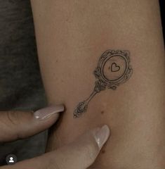 a close up of a person's arm with a clock tattoo on her left shoulder