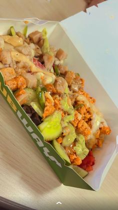 a box filled with lots of food sitting on top of a wooden table next to a paper bag