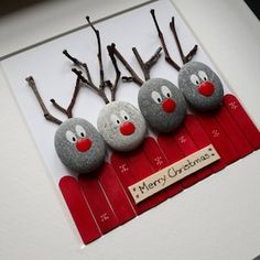 three rocks with reindeer noses on them sitting in front of a white card that says merry christmas