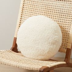 a white round pillow sitting on top of a wooden chair