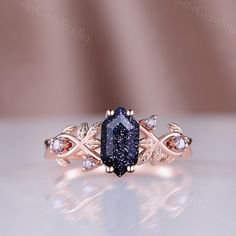 a fancy ring with a blue stone surrounded by white and pink diamonds on a table