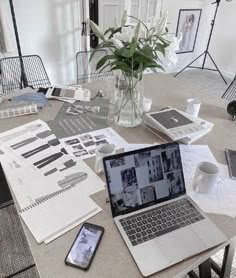 an open laptop computer sitting on top of a table next to a vase with flowers