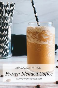 a tall glass filled with coffee next to two straws