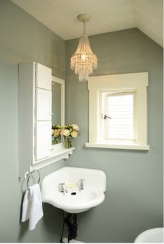 a white sink sitting under a window in a bathroom