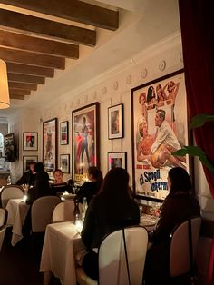 people sitting at tables in a restaurant with posters on the wall