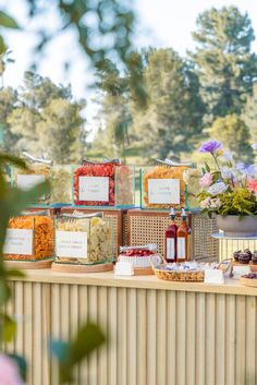 food is displayed on a table in front of flowers and other items that include condiments