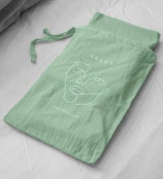 a green bag sitting on top of a bed with an animal drawn on it's side