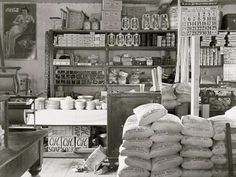 a black and white photo of a store with lots of bags on the counter,