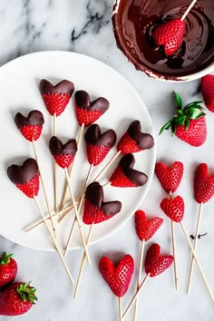 chocolate covered strawberries are arranged on skewers next to a bowl of melted chocolate