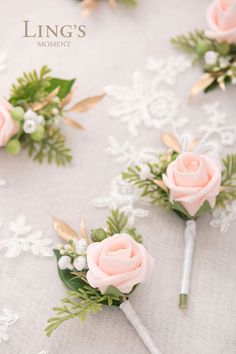 wedding boutonnieres with pink roses and greenery on a lace tablecloth