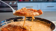 a pizza being lifted from a skillet by a spatula with gravy