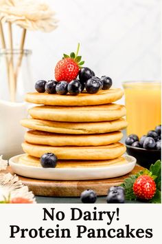 A stack of vegan protein pancakes are on a white plate on the kitchen table. Fresh blueberries and strawberries are on the plate. Juice and flowers are blurred in the background. Text on the image reads, "no dairy! protein pancakes". Protein Pancakes Recipe, Pancake Stack, Pancakes Ingredients