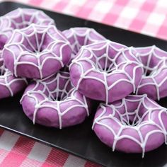 purple sprinkled cookies with white icing on a black plate