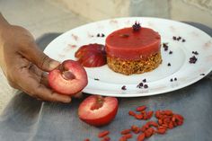 a person holding an apple on a plate with other fruits and nuts around it,