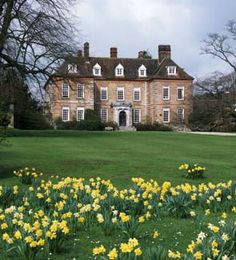 a large brick house with many windows and lots of flowers in the front lawn area