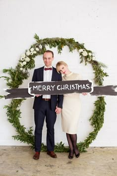 a man and woman holding a merry christmas sign