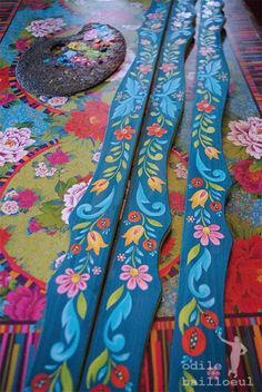 two wooden skis laying on top of a colorful table cloth with flowers and leaves