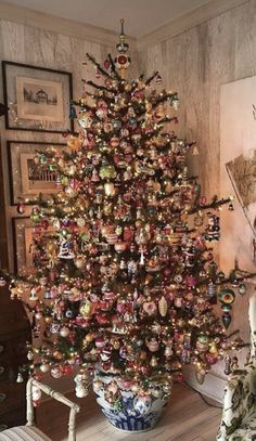 a decorated christmas tree in a living room with pictures on the wall and below it