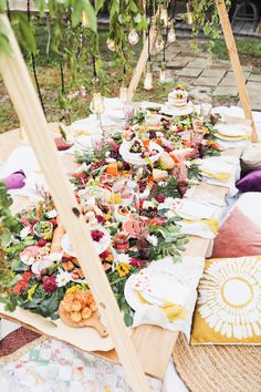 a long table covered with lots of food and flowers on it's tables outside