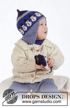 a small child wearing a knitted hat and holding something in his hand while sitting down