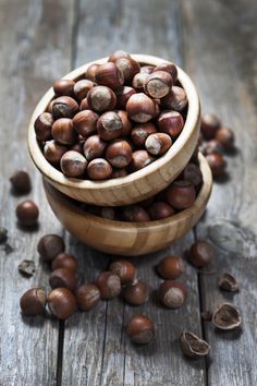 two wooden bowls filled with nuts on top of a wooden table