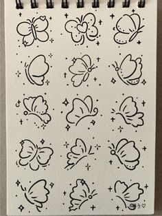 a drawing of butterflies and stars on a sheet of paper with black marker pens in front of it