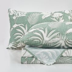 two pillows with green and white designs on them, one is folded over the other