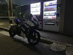 a motorcycle parked next to a vending machine on the side of a road at night